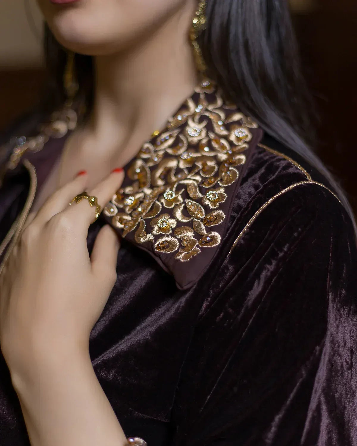 Close-up of the bronze, emerald, and pearl embellishments on the caftan collar.