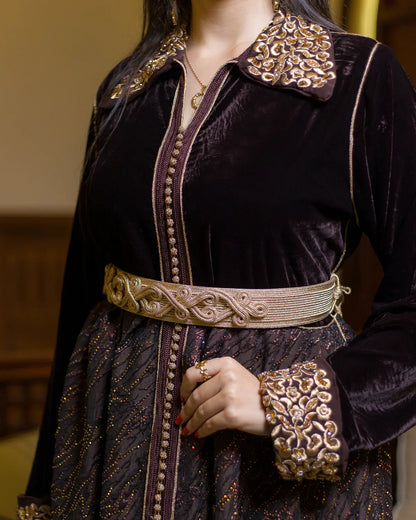Close shot of the golden waist belt and central embroidery on the brown velvet dress.