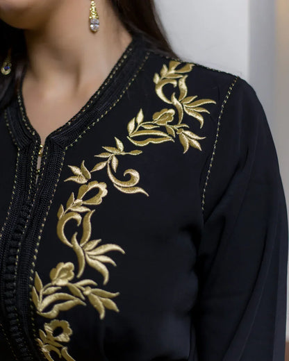 Detailed close-up of the traditional golden embroidery on black caftan shoulder